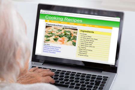 Close-up Of Senior Woman Using Laptop For Learning Recipe On Website At Homeの写真素材