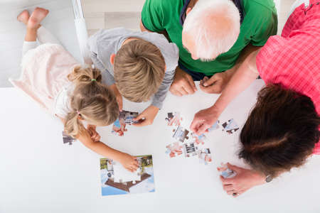 Family Holding Jigsaw Puzzle Pieces While Playing Game With Kidsの写真素材