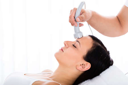 Close-up Of A Relaxed Woman Receiving Microdermabrasion Therapy On Forehead