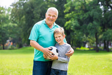 Grandfather Playing Soccer Game With Kid Together In The Parkの写真素材