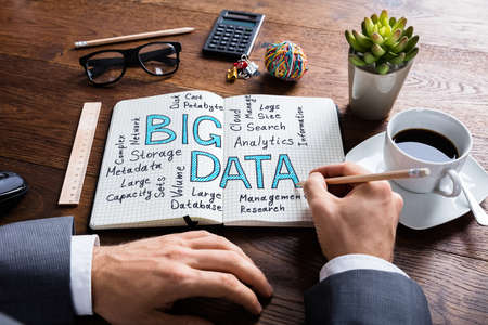 Businessman Writing On A Notebook About Big Data At Wooden Desk In Officeの写真素材