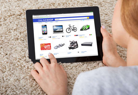 Close-up Of Woman On Carpet Shopping Online On Digital Tablet At Homeの写真素材