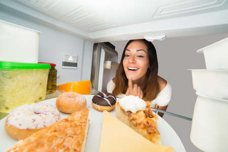 Excited Young Woman Looking At Sweet Food On Plate In Refrigerator