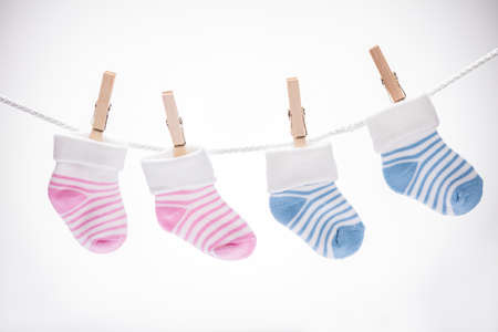 Two Pairs Of Baby Sock Hanging On Rope Using Wooden Clip Against White Backgroundの写真素材