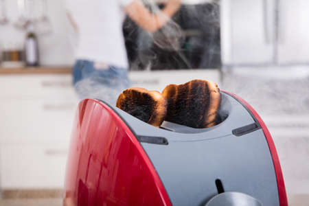 Close-up Of Burnt Toast Coming Out Of Toaster In Kitchenの写真素材