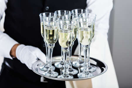 Waiter Standing With Champagne Glasses Next To Arranged Wedding Tableの写真素材