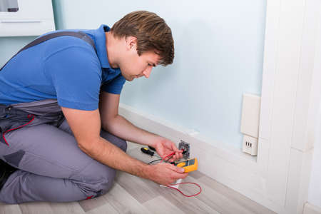 Electrician Checking Socket Voltage Using Multimeter In A Wall Fixture