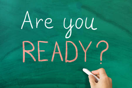 Close-up Of Person Handwritten Are You Ready Text On Notepad At Wooden Deskの写真素材