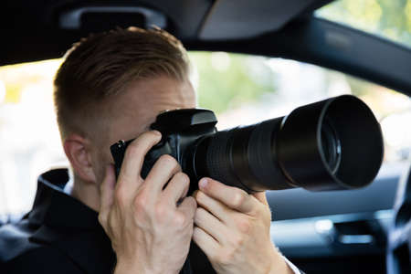 Private Detective Sitting Inside Car Photographing With SLR Cameraの写真素材