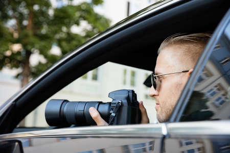 Man Doing Surveillance Sitting Inside Car Photographing With SLR Cameraの写真素材