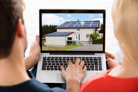 Close-up Of A Young Couple Looking At House On Laptop At Home