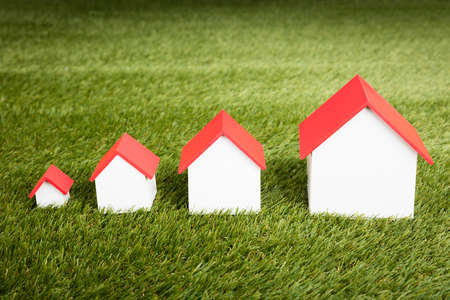 Different Size Of Houses Arranged In Row On Grassy Fieldの写真素材