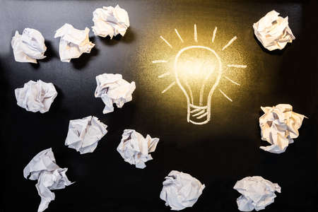 Pieces Of Crumpled Paper With Illuminated Light Bulb On Blackboard