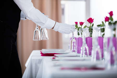 Close-up Of Waiter Setting Wedding Table At Restaurantの写真素材