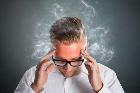 Angry Stressed Young Businessman Becoming Red. Unhappy Employee Conceptの写真素材