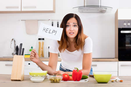 Portrait Of Young Woman Holding Help Flag In Kitchenの写真素材