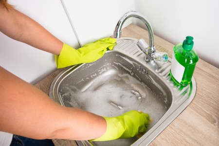 Close-up Of Woman Cleaning The Sink In The Kitchen With Liquid Detergentの写真素材