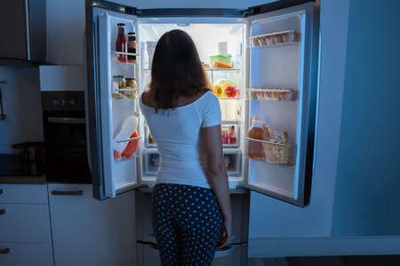 Rear View Of Young Woman Looking In Fridge At Kitchenの写真素材