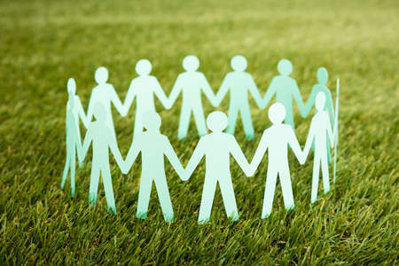 Close-up Of White Papercut Of People Chain On Grassの写真素材