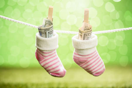 Pair Of Baby Sock With Dollar Hanging On Rope Using Wooden Clipの写真素材
