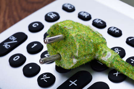 Close-up Of Green Eco Electric Cable On Calculator Buttonの写真素材