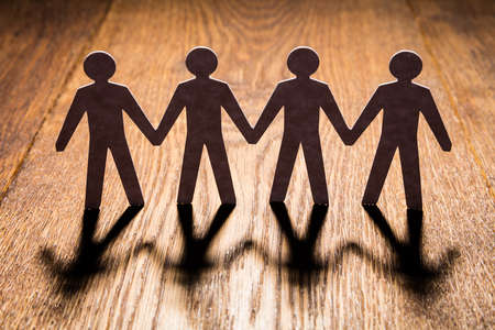 Silhouette Of Papercut People On Wooden Deskの写真素材