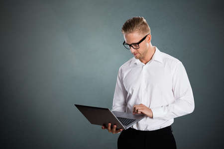 Businessman Using Laptop Computer Against Grey Backgroundの写真素材
