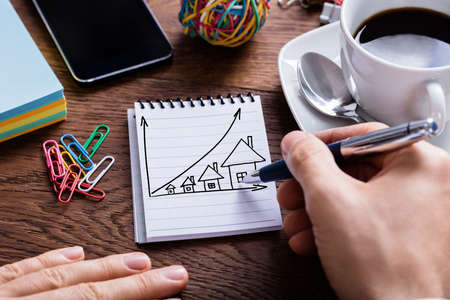 High Angle View Of Person Drawing House Prices Growth Concept On Notepadの写真素材