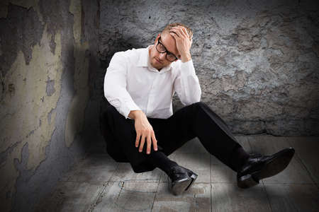Young Worried Man Sitting In Abandoned Roomの写真素材