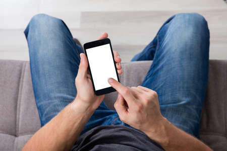 Elevated View Of A Man Sitting On Couch Using Cell Phoneの写真素材
