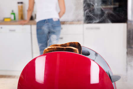 Close-up Of Burnt Toast Coming Out Of Toaster In Kitchenの写真素材