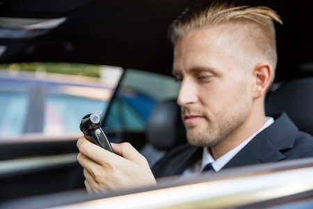 Man Sitting Inside Car Looking At Breathalyzer Testの写真素材