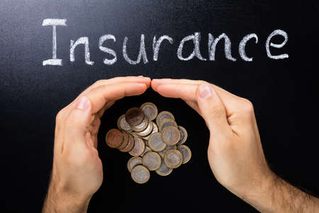 Person Hand Protecting Coins Showing Insurance Concept On Blackboardの写真素材