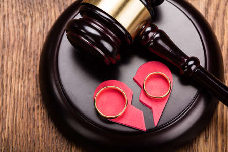 High Angle View Of Golden Ring On Red Broken Heart At Wooden Gavel In Courtの写真素材