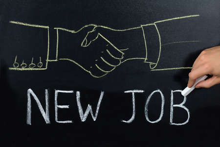 Close-up Of Person Hand Showing New Job Concept On Blackboardの写真素材