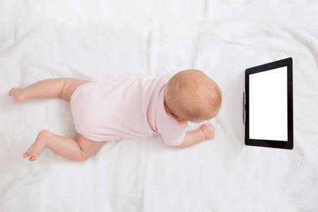 Cute Baby Looking At Digital Tablet While Lying On Bed