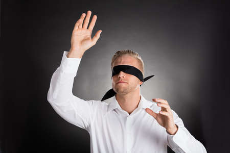 Young Blindfolded Confused Businessman Against Grey Backgroundの写真素材