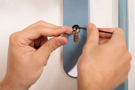 Close-up Of Lockpicker Hand Opening Door Lock