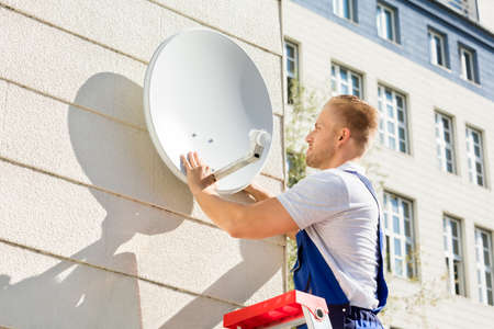 Young Man Fitting TV Satellite Dish To Wallの写真素材