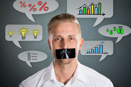 Businessman With Black Duct Tape Over His Mouth With Business Symbol At Backgroundの写真素材