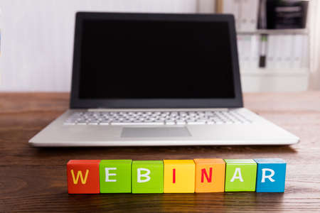 Webinar Text On Blocks In Front Of Laptop Over Wooden Deskの写真素材