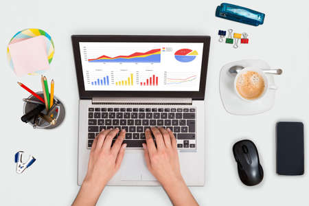 High Angle View Of A Person Hand Analyzing Financial Graph On Laptop At Office Deskの写真素材