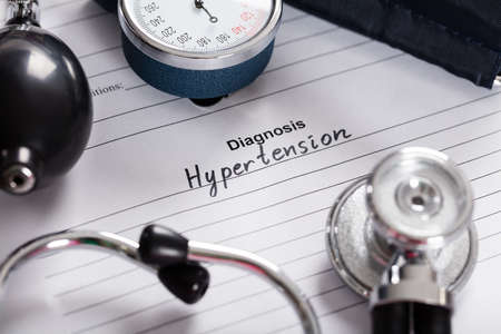 Close-up Of Text Diagnosis Hypertension;Stethoscope And Blood Pressure Gauge On Medical Form