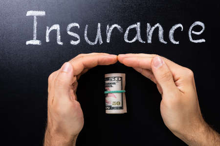 Person Hand Protecting Rolled Dollar Banknotes On Blackboardの写真素材