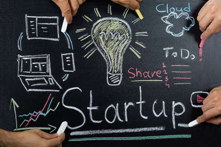 Close-up Of People Working On Startup Plan On Blackboard