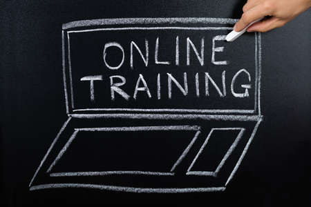 Close-up Of Person Hand Showing Online Training Program Written On Blackboard