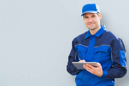 Portrait Of A Young Delivery Man Holding Clipboard On Colored Backgroundの写真素材