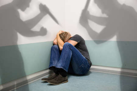 Shadow Of Two People Attacking Abuse Man Sitting At The Corner Of A Room