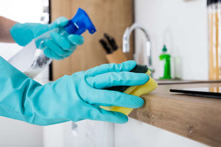Janitor Cleaning Kitchen Worktop With Sponge And Spray Bottleの写真素材