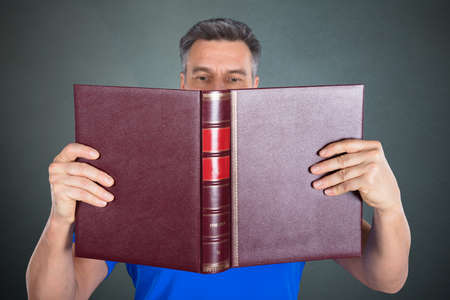 Close-up Of A Man Reading A Book On Gray Backgroundの写真素材